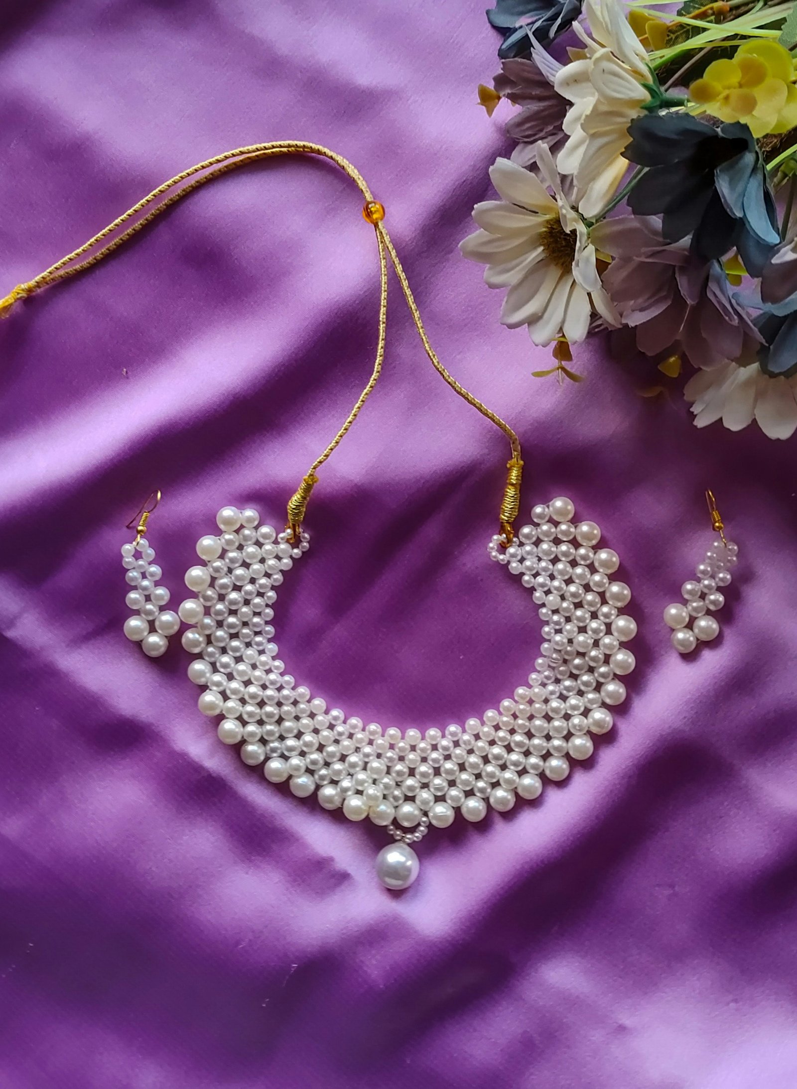 Collier et bouquet de fleurs sur un tissu violet