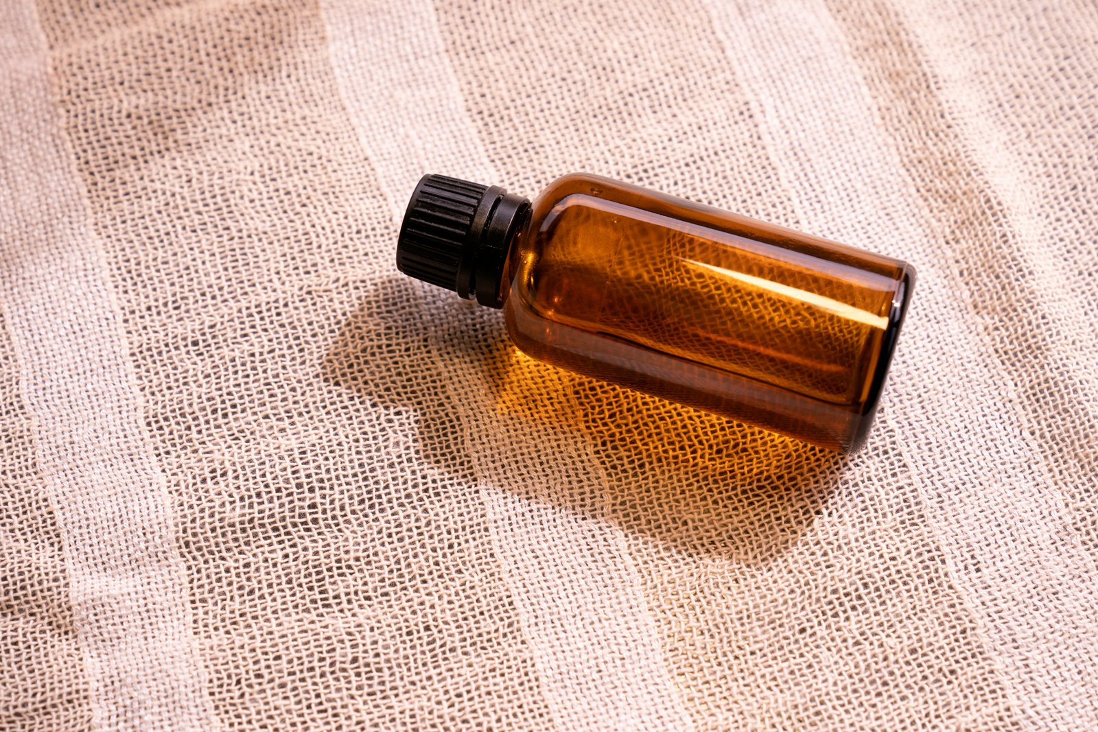 Flacon d’huile de soin posé sur un tissu